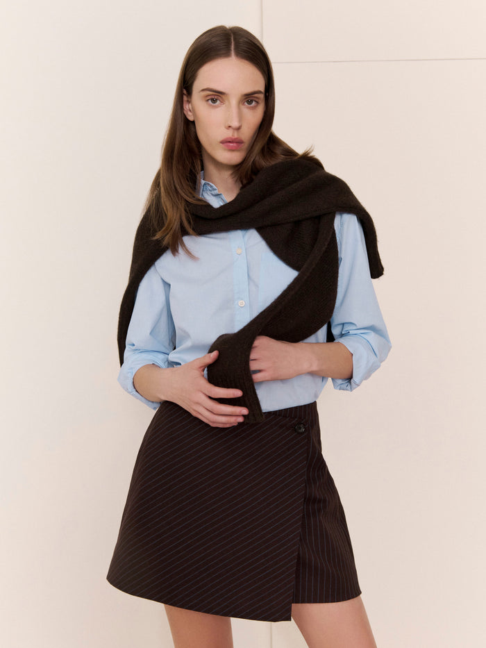 Woman wearing a black scarf and skirt against a plain background