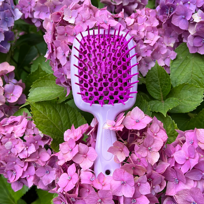Janeke Hairbrush with purple bristles on a background of pink and purple flowers