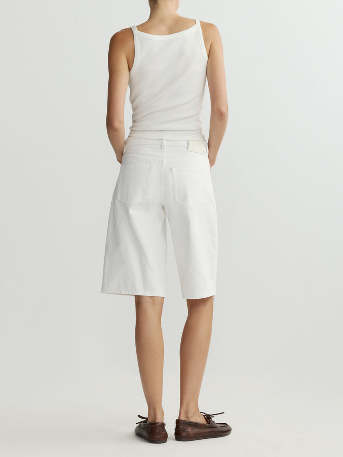 Person wearing a white sleeveless top and shorts on a plain background