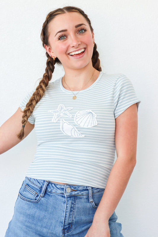 girl wearing light blue stripped t-shirt with seashell patches