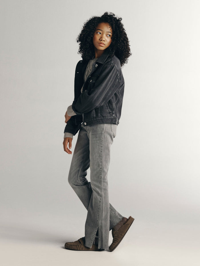 DL1961 girls' Claire bootcut jeans in light grey 'Twister' with a charcoal denim jacket, side profile on model.