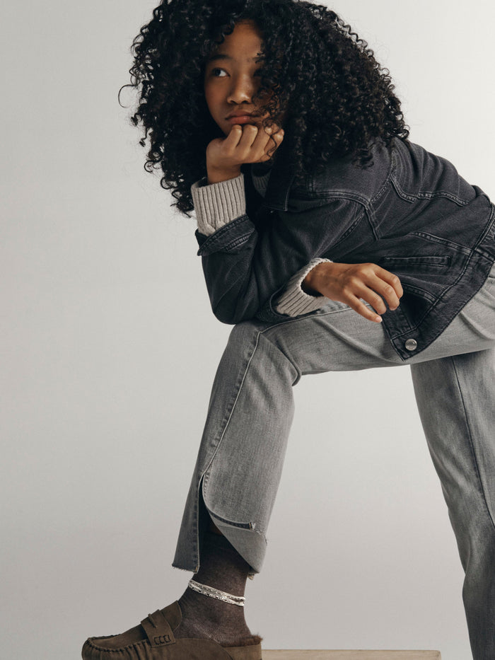 DL1961 girls' Claire bootcut jeans in light grey 'Twister', seated three-quarter view on model.
