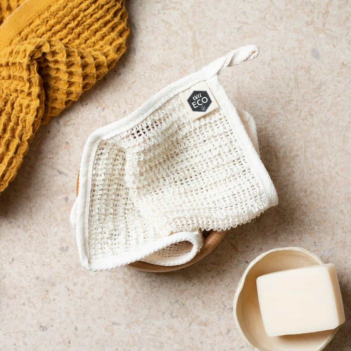 Sisal cloth folded up next to a bar of soap and a yellow textured towel.