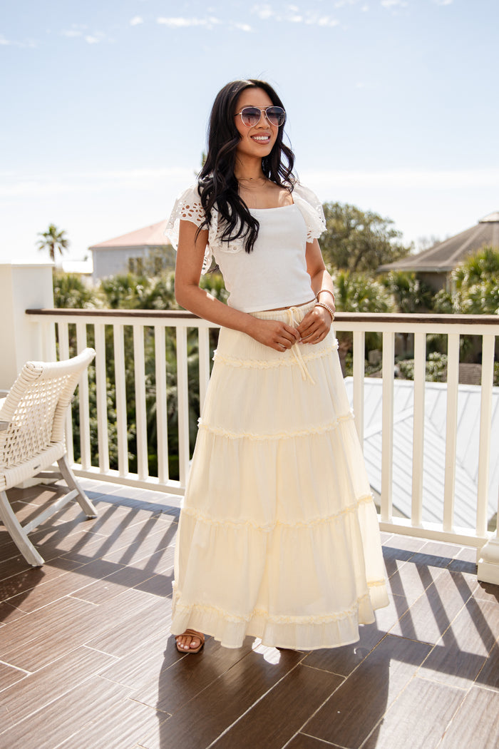 Woman in a white dress standing on a balcony with a scenic background