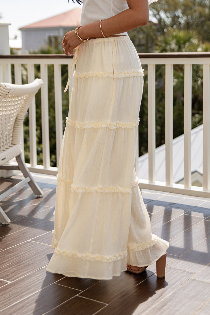 Person wearing a long, light-colored skirt on a wooden deck.