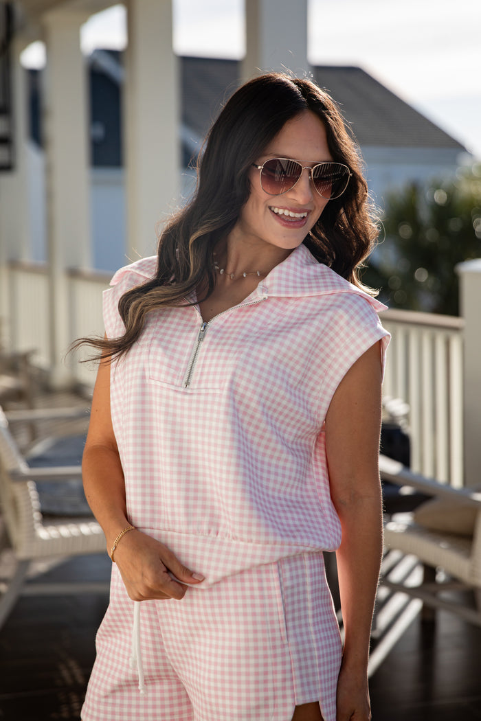 woman wearing a pink gingham quarter zip collared tank top