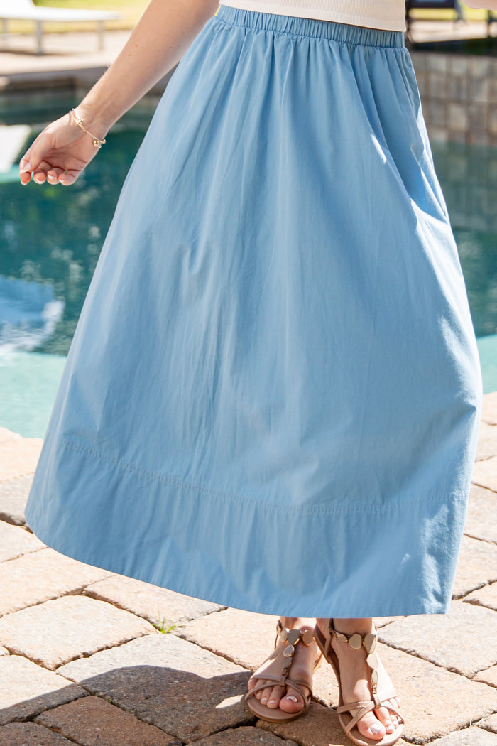 Person wearing a light blue skirt by a poolside