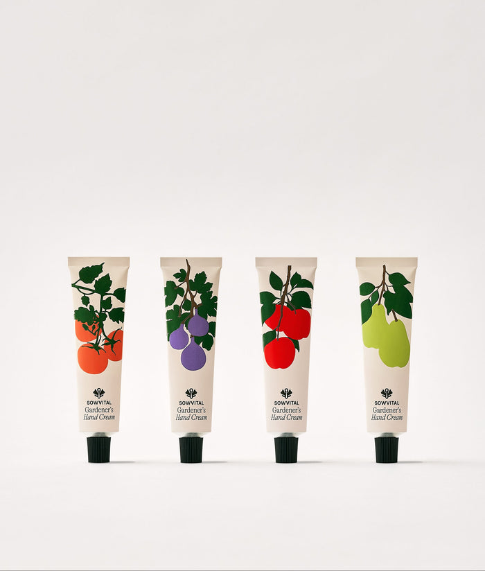 Four tubes of hand cream with fruit illustrations on a white background.