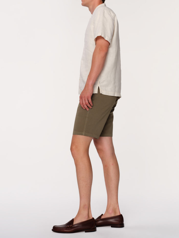 DL1961 men's Jake chino short in olive green 'Belfast', side view on model with cream shirt and loafers.