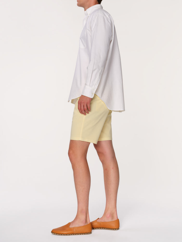 DL1961 men's Jake chino short in pale yellow 'Citron', side view on model in white shirt.