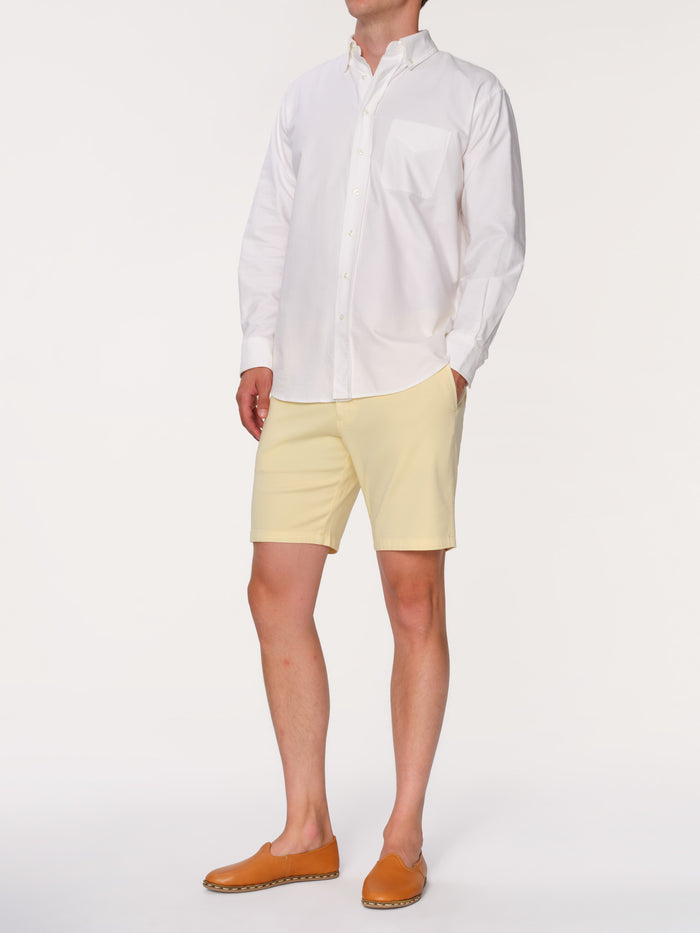 DL1961 men's Jake chino short in pale yellow 'Citron', three-quarter view on model in white shirt.