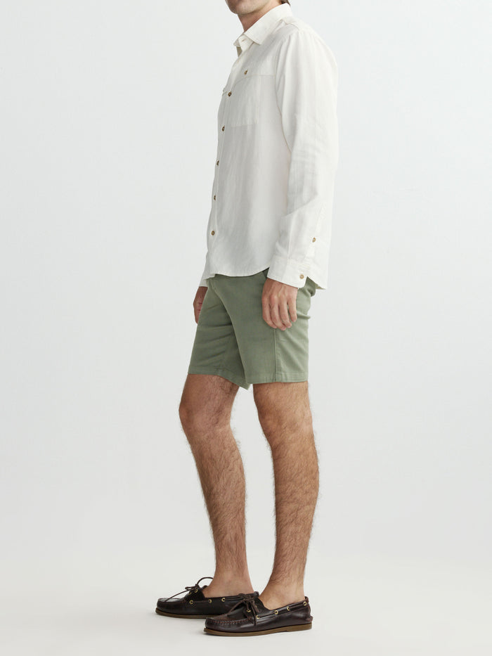 Person wearing a white shirt and green shorts on a plain background