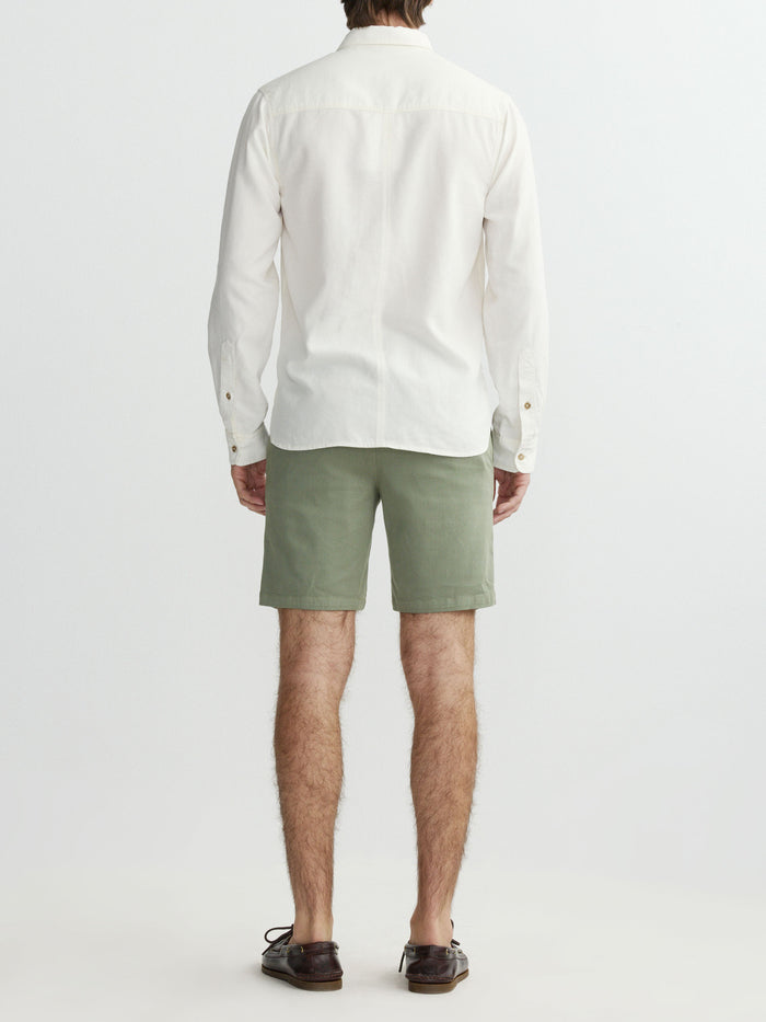 Person wearing a white shirt and green shorts on a plain background