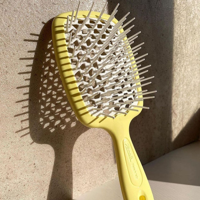 Janeke Yellow hairbrush with metal bristles on a textured surface