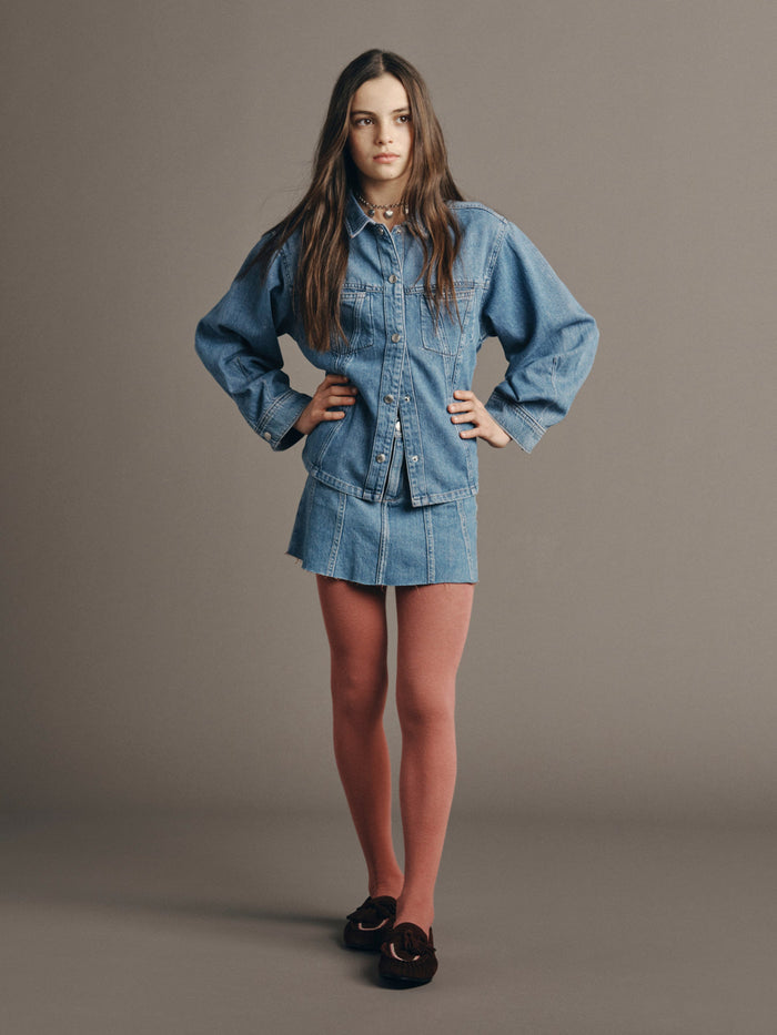DL1961 girls' Jenny mini skirt in medium blue 'Indigo Rose' with denim shirt and pink tights, front view on model.