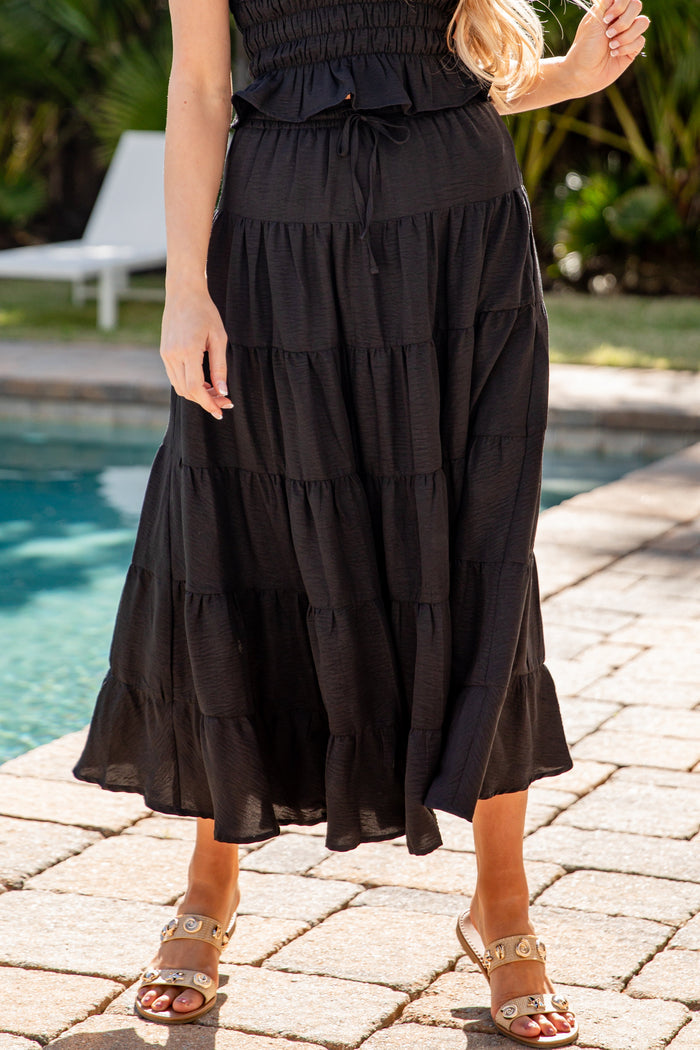 Woman wearing a black tiered dress by a poolside