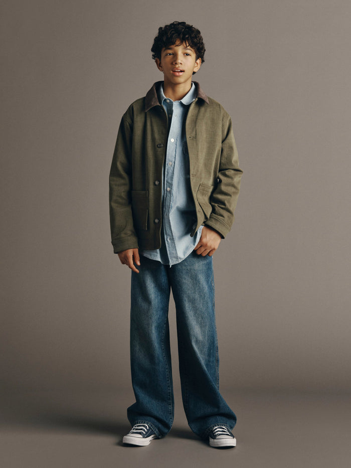 DL1961 boys' Louie denim chore jacket in olive 'Outpost' over a blue shirt with wide-leg jeans, full-length front view.