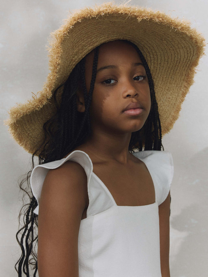 DL1961 girls' Meredyth mini dress in white 'White', close-up of ruffle strap and straw hat.