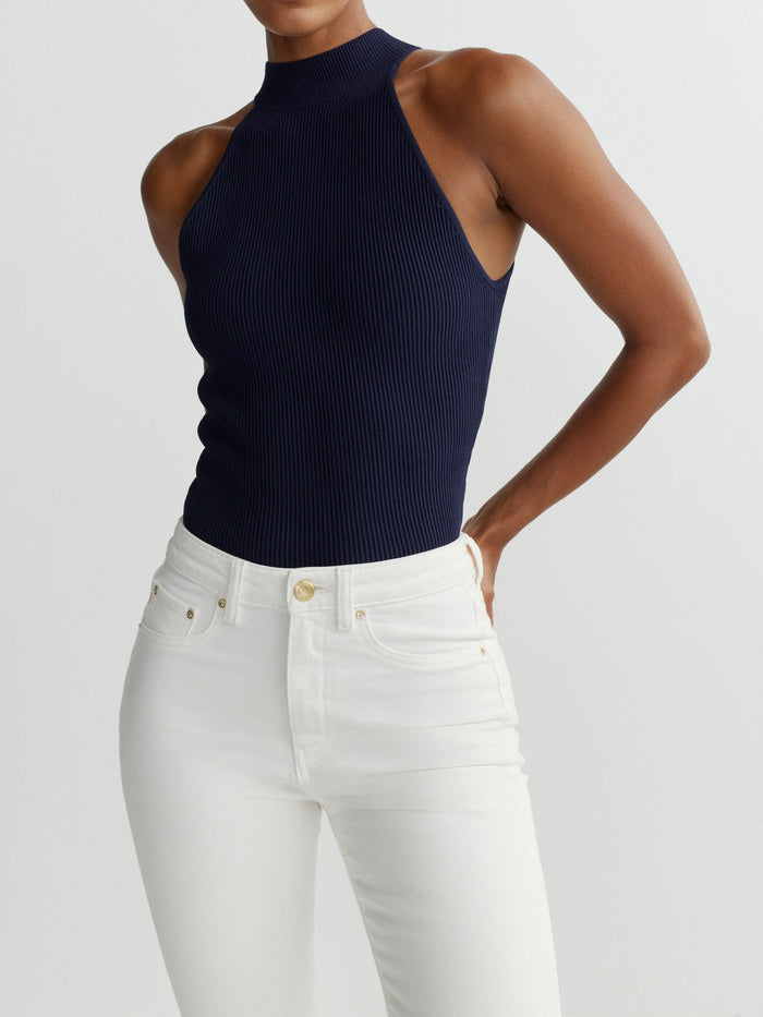 DL1961 women's Mock Neck Top in navy 'Bright Navy', ribbed knit, three-quarter view on model with white jeans.