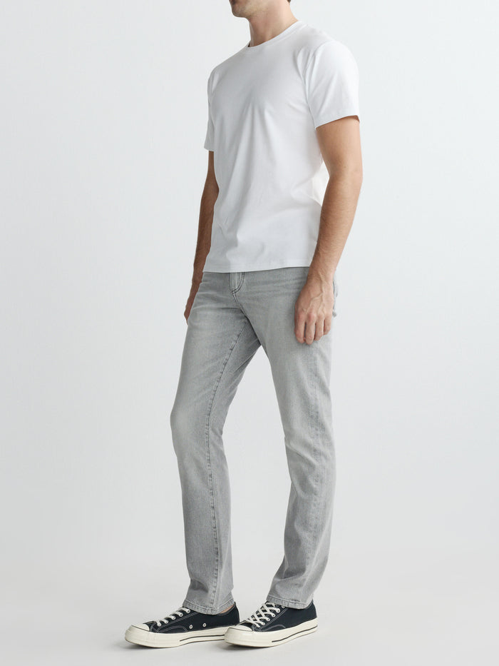 DL1961 men's ribbed crewneck tee in white 'White', three-quarter side full-length with grey jeans.