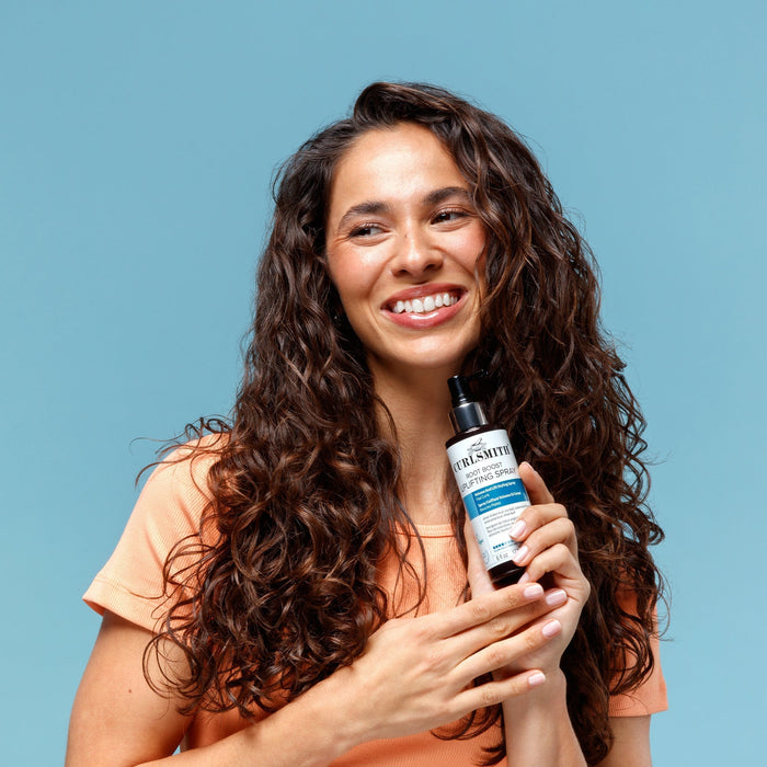 Woman holding a bottle of hair care product against a blue background