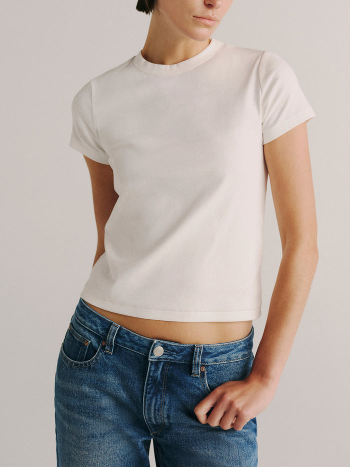 DL1961 Shrunken Tee in white, a fitted cropped crew-neck tee, worn with blue jeans, front view.