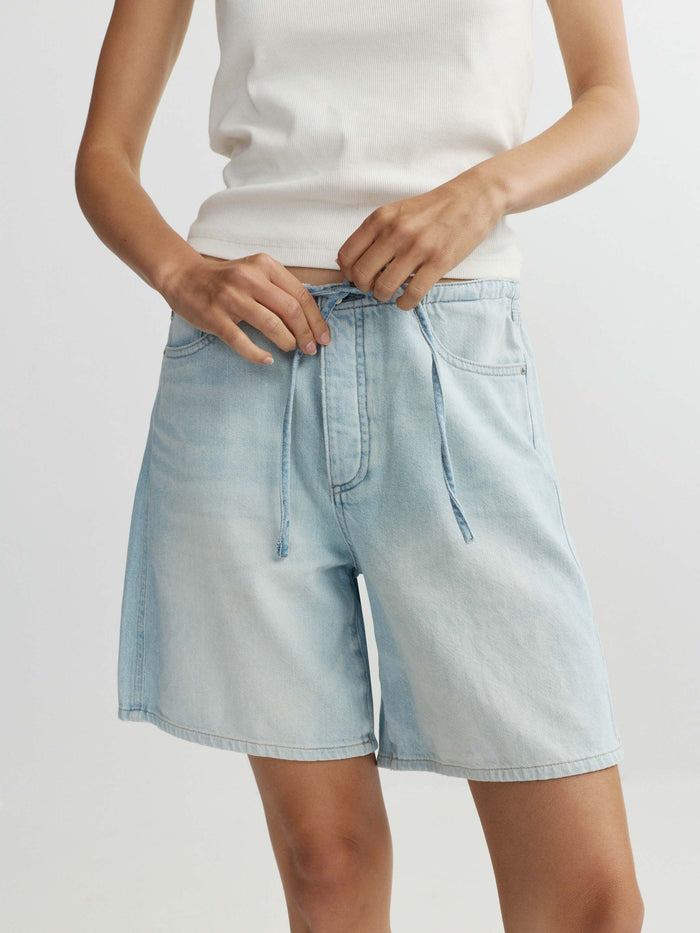Light blue denim shorts worn by a person on a plain background