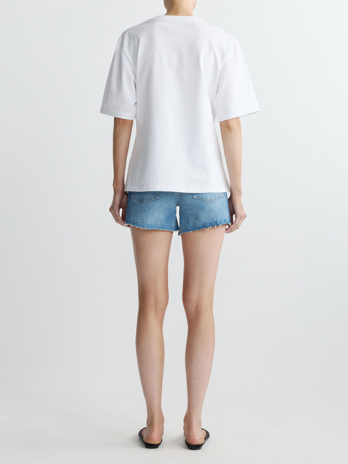 Person wearing a white t-shirt and denim shorts on a plain background